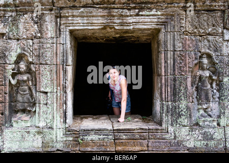 A tourist posing in a window at a temple in Angkor, Cambodia Stock Photo