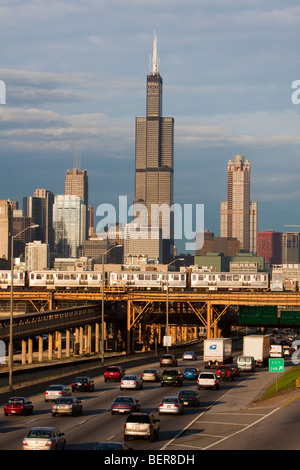 The Sears (Willis) Tower rises over the city of Chicago as rush hour traffic and L trains pass below. Stock Photo