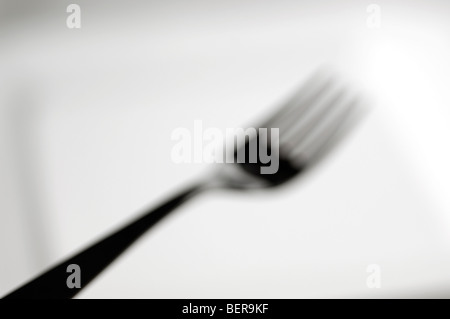 Fork in silhouette on white plate - out of focus Stock Photo