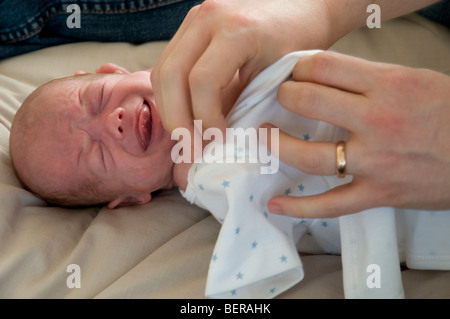 Close up of a mother dressing a crying baby Stock Photo