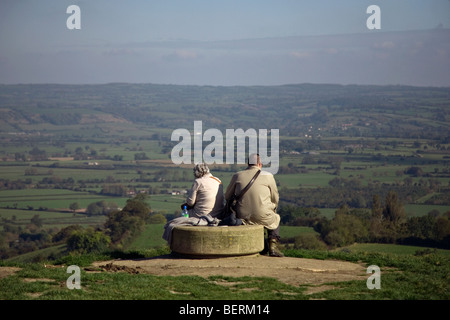 two people looking out from Glastonbury Tor in Somerset England Stock Photo