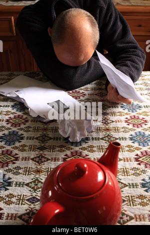 Middle aged man upset depressed with receiving financial bills and demands through the post mail - posed by model Stock Photo