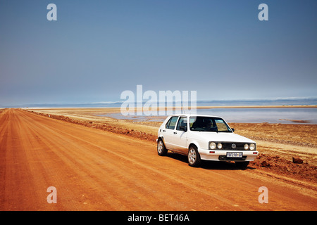 white car parked on red dust road, Namibia Stock Photo