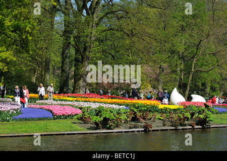 Tourists walking among colourful tulips, hyacinths and daffodils in flower garden of Keukenhof, Lisse, Holland, the Netherlands Stock Photo
