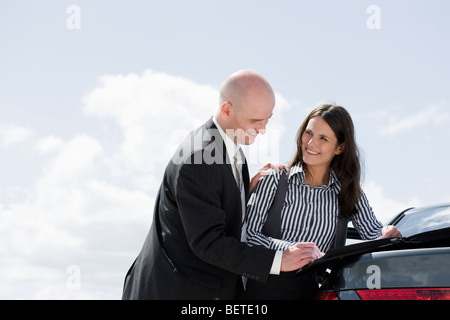 man signing contract on back of car Stock Photo