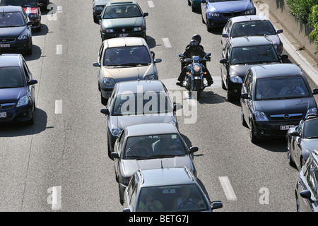 Motorcyclist riding between cars in traffic jam on motorway during the summer holidays, Belgium Stock Photo