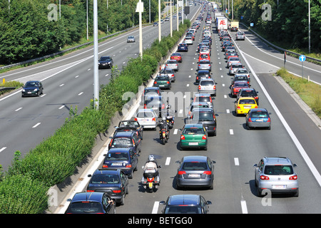 Cars and motorcyclists queueing in highway lanes at approach slip road during traffic jam on motorway during summer holidays Stock Photo