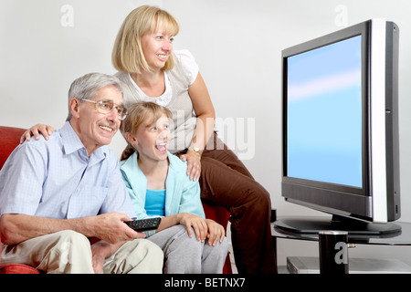 Three generations watching tv together, Mum, Daughter and Grandad. Stock Photo