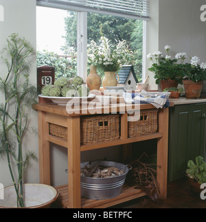 Wicker storage baskets in small pine table below window in kitchen Stock Photo
