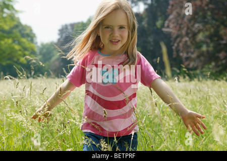 young girl walking through a meadow touching the long grass Stock Photo