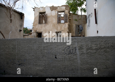 wall enclosing bombed out buildings in no mans land and restricted area of the UN buffer zone in the green line Stock Photo