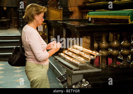 Woman (probably with Polish nationality) lights a vigil candle in the church of St Marys Basilica. Krakow. Poland. Stock Photo