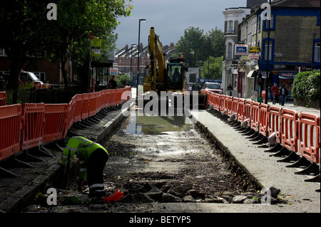 Cat digger in Crouch hill , North London seen in use resurfacing the road at the  bus stop area. Stock Photo