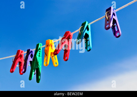 Colorful clothes pegs on line against blue sky Stock Photo