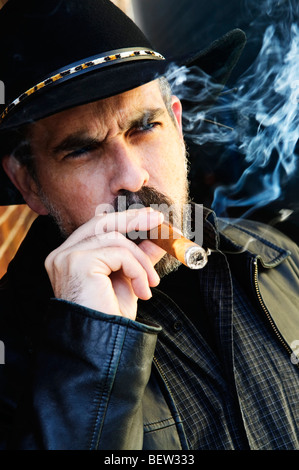 Man with beard in cowboy hat smoking cigar Stock Photo