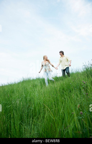 A young couple walking through a meadow, low angle view Stock Photo