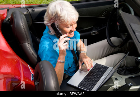 Woman notebook and mobile phone sitting ina convertible, elevated view Stock Photo