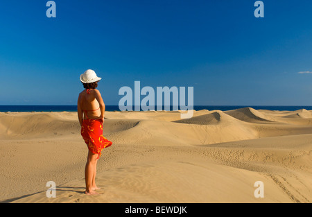 Woman standing on a sand dune looking at the sea, Maspalomas, Gran Canaria, Spain, rear view Stock Photo