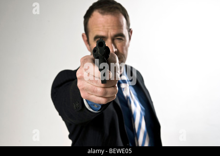 Businessman aiming a gun at camera, front view Stock Photo