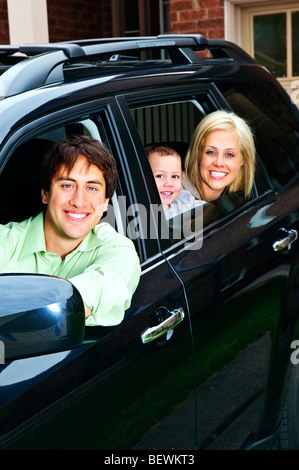 Happy young family sitting in black car looking out windows Stock Photo