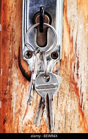 Set of keys in lock of old wooden door Stock Photo