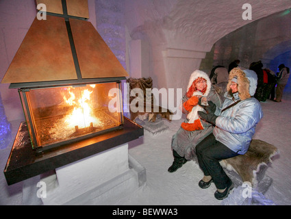 Two women sit by fire in N'Ice Club (lounge) of Ice Hotel at Duchesnay, government park in Quebec Province outside Quebec City. Stock Photo