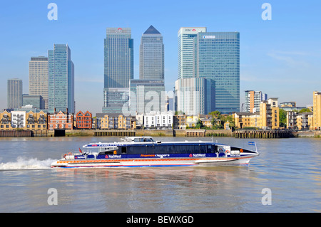 Thames clipper fast catamaran river waterbus service passing Canary Wharf skyline on the Isle of Dogs Stock Photo