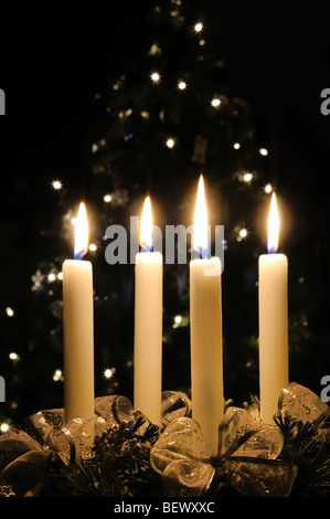 Christmas advent wreath with burning candles. Lights on x-mas tree in background Stock Photo