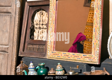 Woman with traditional islamic dress reflected in a mirror in the street of Marrakech medina. Marrakech, Morocco North Africa Stock Photo
