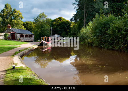 Picturesque reflection of boat house and moored canal boat on the Monmouth and Brecon Canal taken at Llangynidr mid Wales Stock Photo