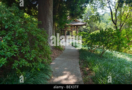 Lush walkway towards a large iron bell in the Japanese Gardens of the Huntington Library. Stock Photo