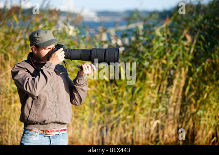 Young nature photographer with taking photos using telephoto lens Stock Photo