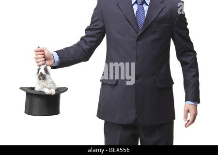 Businessman pulling a rabbit out of a silk top hat Stock Photo