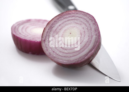 A red onion sliced in half on a white backgroundwith a knife Stock Photo