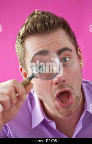 Young man looking through magnifying glass Stock Photo