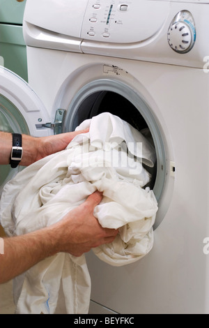 A man loading a washing machine Stock Photo