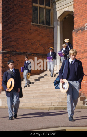 Harrow on the Hill , Harrow School pupils or students in uniform walking in grounds with traditional straw boaters at lunchtime Stock Photo