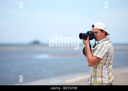 Young photographer taking photos at the beach Stock Photo