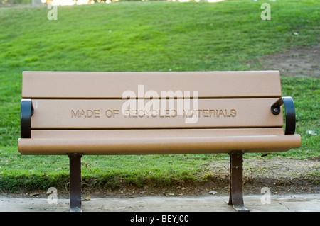 Park bench with a prominently displayed message indicating that it is manufactured with recycled materials. Stock Photo