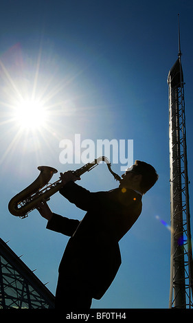 Silhouette of a man playing a saxophone with the Glasgow Science Center in the background. Stock Photo