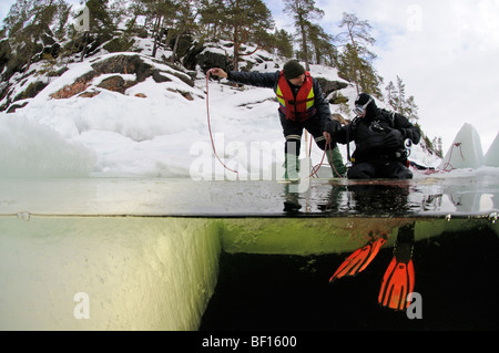 split shot from ice diving, ice diver sitting on the ice hole, White Sea, Russia Stock Photo