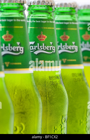 A Row Of Green Carlsberg Beer Bottles with The Middle Bottle In Focus Stock Photo