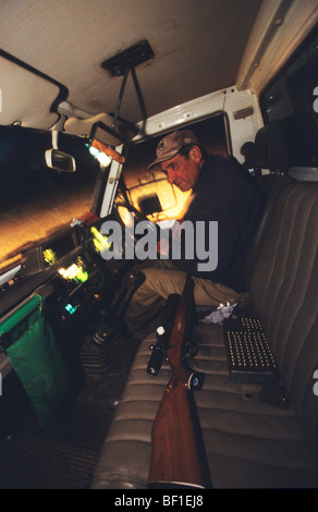 Kangaroo hunter in outback, with rifle and bullets in vehicle at night, Australia Stock Photo