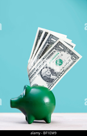 A green piggy bank with dollar bills sticking out of it Stock Photo