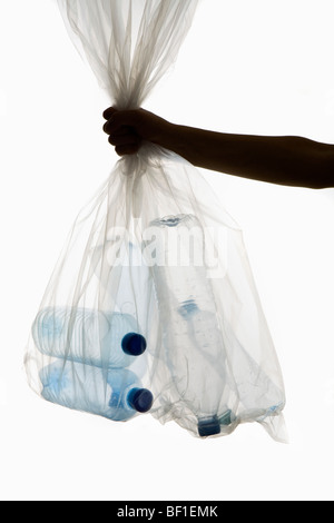 A human hand holding a transparent garbage bag of plastic bottles Stock Photo
