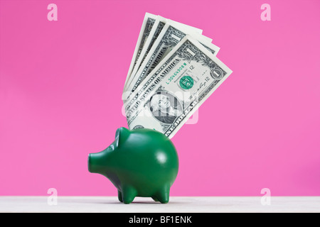 A green piggy bank with dollar bills sticking out of it Stock Photo