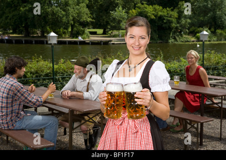 A traditionally clothed German woman serving beer in a beer garden Stock Photo
