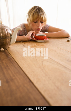 A young woman blowing on a tea cup Stock Photo