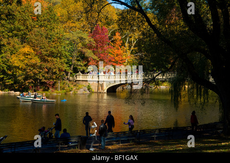 Visitors to Central Park enjoy an autumn day by Central Park Lake and the Bow Bridge in New York Stock Photo