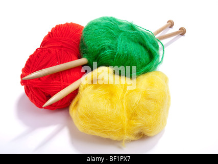 Large ball of red, yellow and green mohair wool or yarn pierced with large wooden knitting needles against white background. Stock Photo